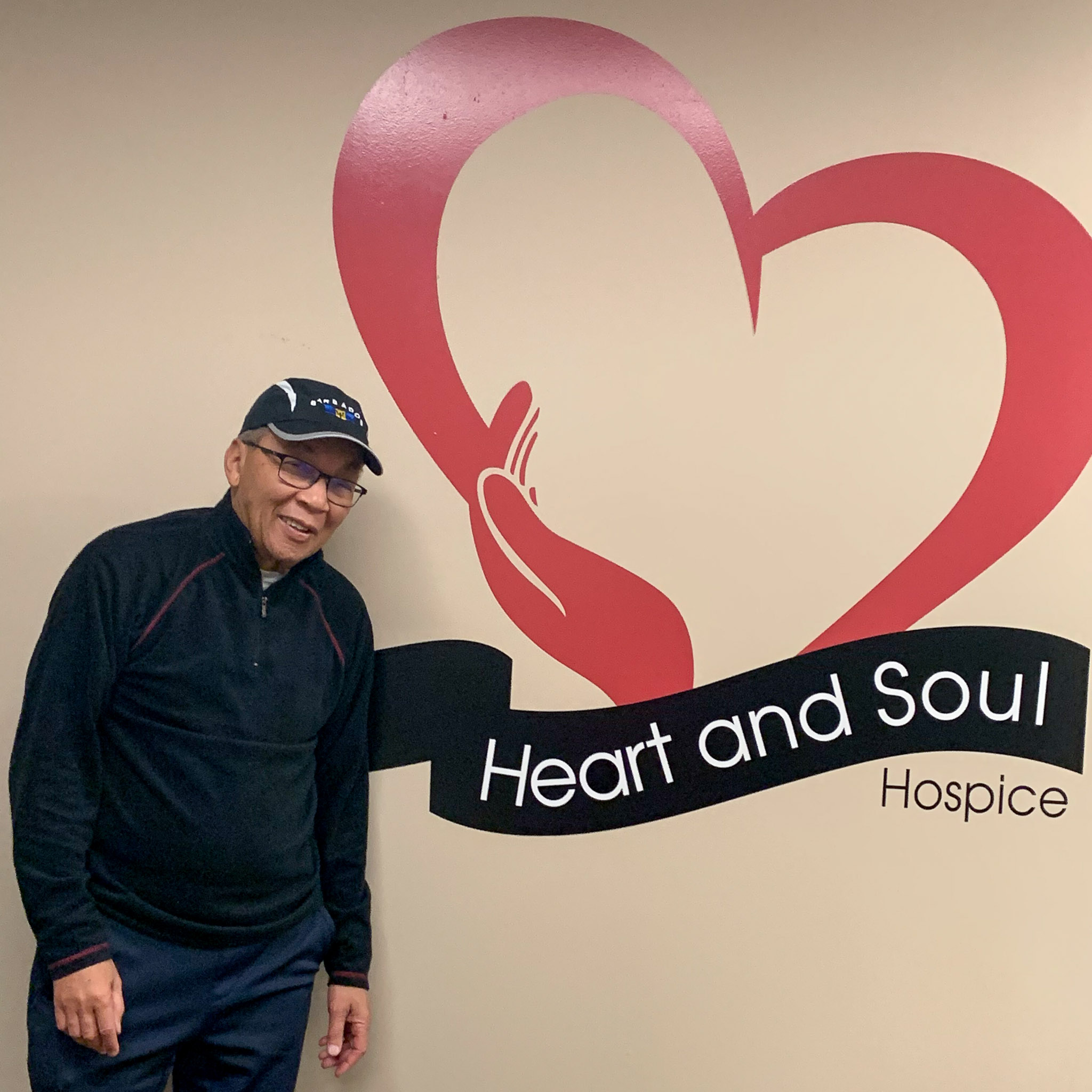 Andre Lee in hat, standing next to logo of Heart and Soul Hospice